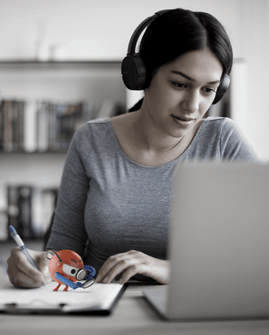 woman wearing headphones in front of a laptop while writing